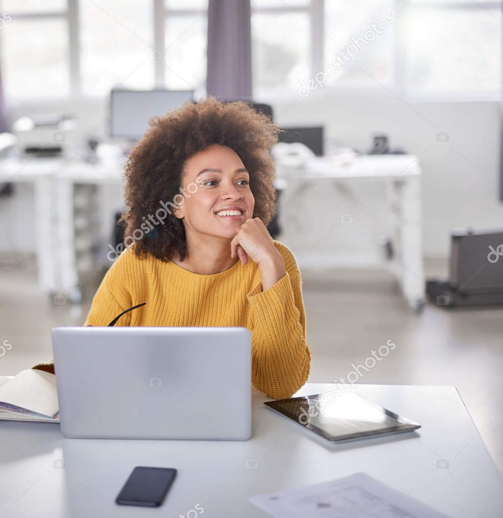 Gorgeous mixed race businesswoman dressed casual sitting at the desk, using laptop and posing in modern office.